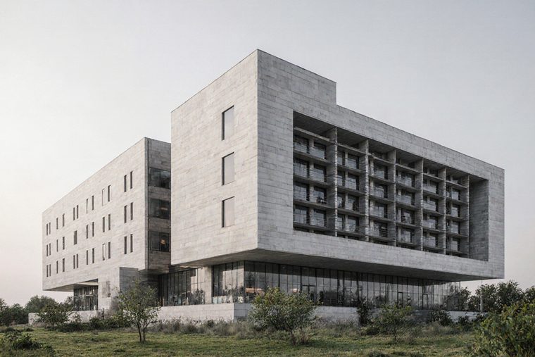 A mid-rise concrete and glass building with a projecting balcony block on one elevation